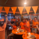 Groep bezoekers in oranje kleding viert samen tijdens een voetbalavond.