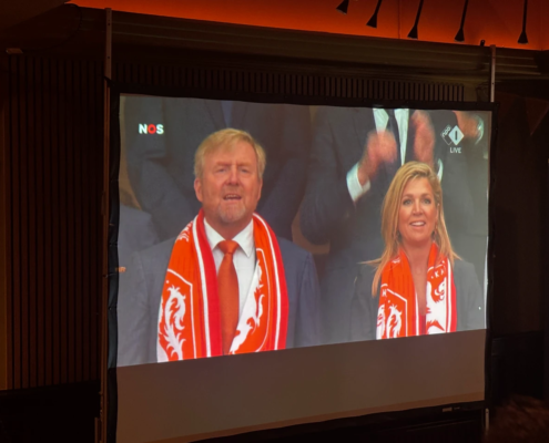 Groot scherm met een live voetbaluitzending tijdens de Oranjeavond.